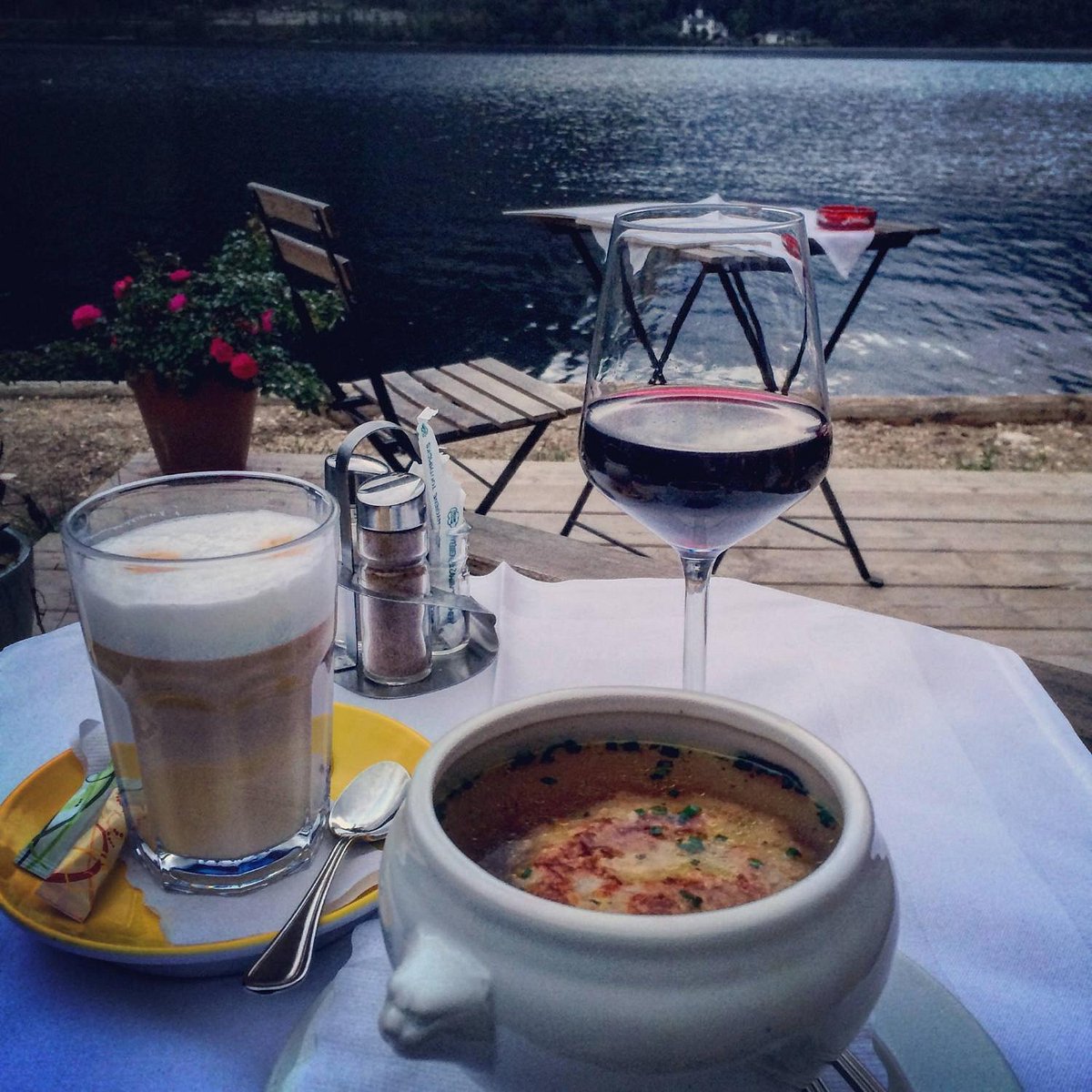 Soup and drinks served at a table directly beside Lake Hallstatt